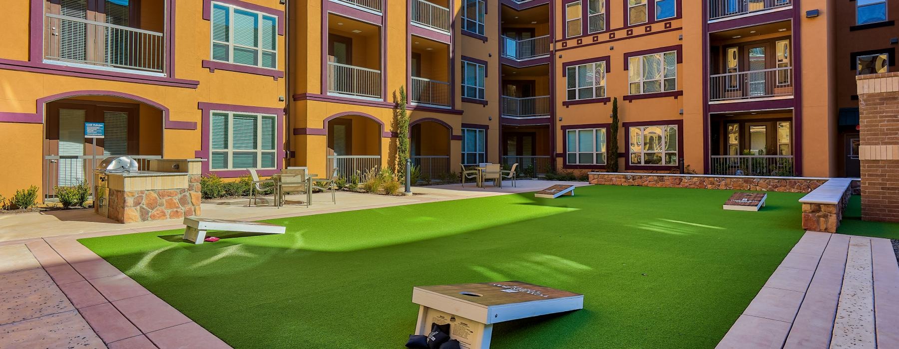 a courtyard with cornhole and a building with many windows
