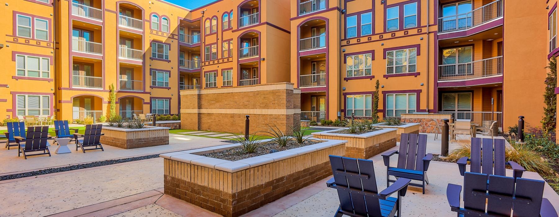 a courtyard with planters and chairs and building in the background