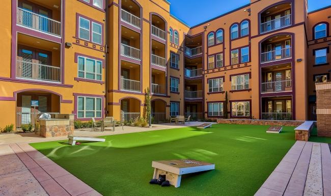 a courtyard with cornhole and a building with many windows